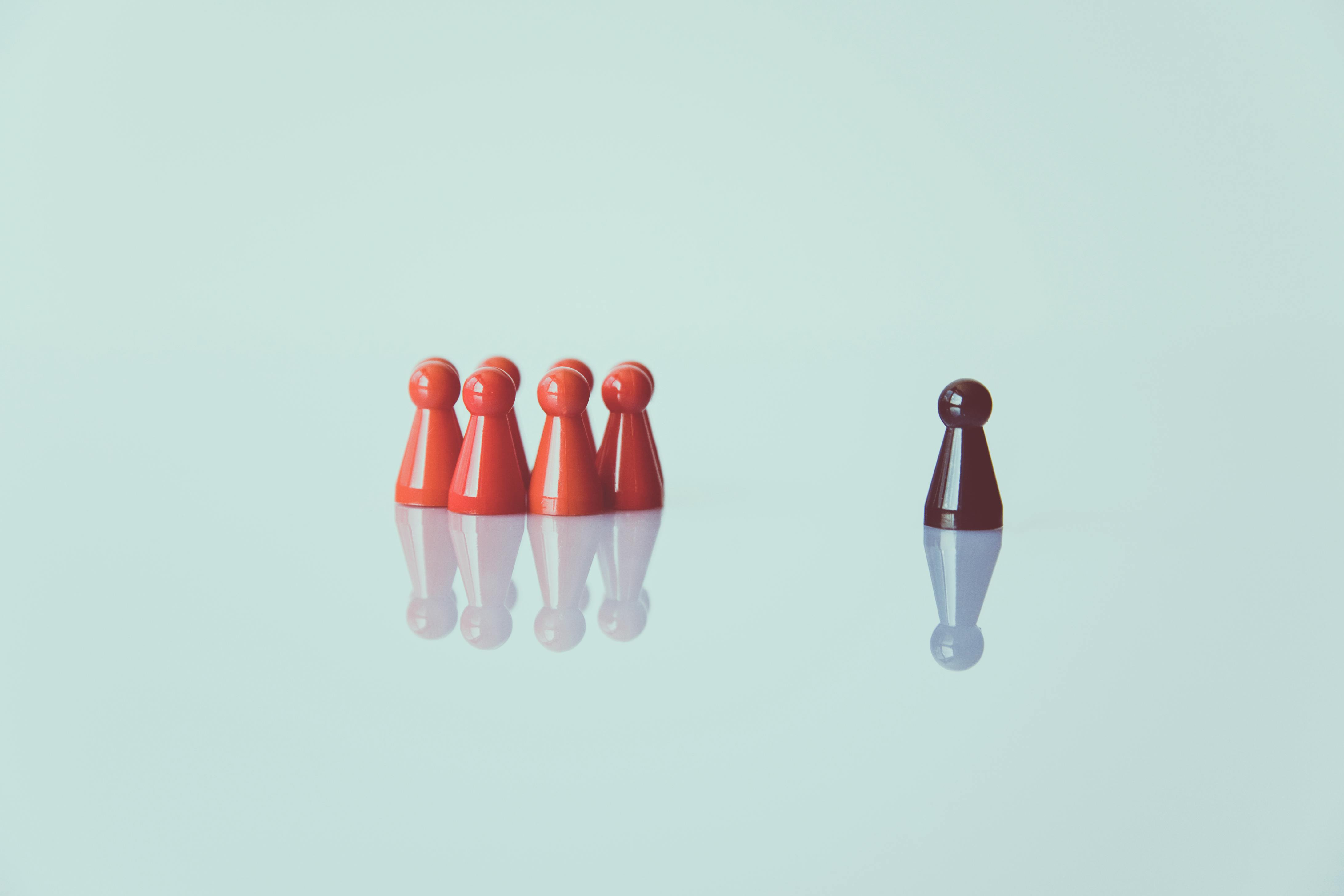 One black pawn stands apart from a group of red pawns